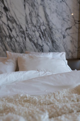 Cozy Bedroom scene with comfortable pillows and white wool blanket with natural white marble on the background / cozy interior concept / luxury design / interior design decoration