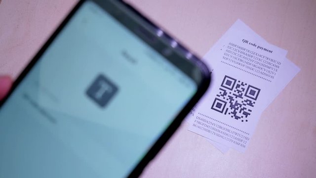 Smart phone scanning QR code in paper label or payment check. Concept of payment , online shopping and cashless technology