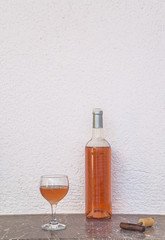 Glass of pink wine and opened bottle on marble table