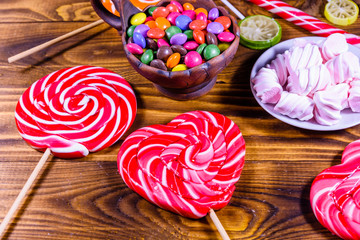 Ceramic plate with marshmallow, candy cane and lollipops on a wooden table