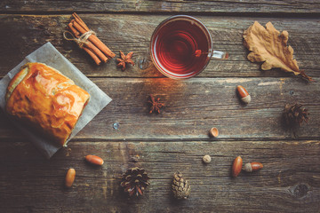 Cup of tea with autumn leaves on wooden background