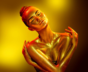 Golden skin woman portrait closeup. Sexy model girl with holiday golden shiny professional makeup....
