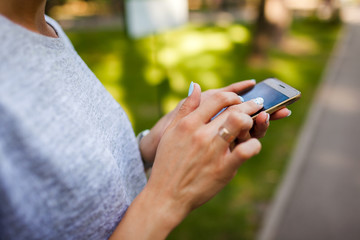 College student using mobile phone in park. Young woman typing message