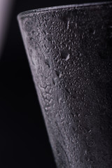 Glass on a dark blurry background with drops of water