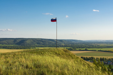 Fototapeta na wymiar Flag on the mountain against the blue sky and horizon