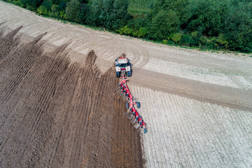 Tractor harrownig the large brown field