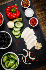 Vegetables for salad on black stone plate wooden background