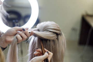 Hairdressing services.Сreating an evening hairstyle. Hair styling process.