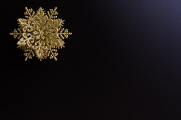 Golden snowflake decoration on the up-left corner of a black gradient background