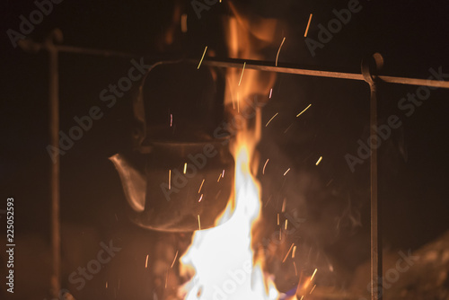 The kettle is heated on a fire at night outdoor