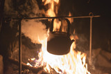 The kettle is heated on a fire at night outdoor