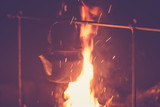 The kettle is heated on a fire at night outdoor, toned photo