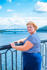 Fototapeta premium Portrait of attractive plus size mature woman in casual style walk at city at good sunny autumn day and thinking about something. Life of women after 40-50 years 