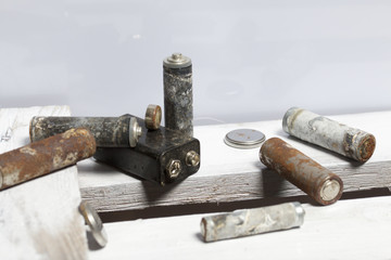 Used finger-wound batteries covered with corrosion. They lie on a wooden box. Recycling.