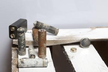 Used finger-wound batteries covered with corrosion. They lie on a wooden box. Recycling.