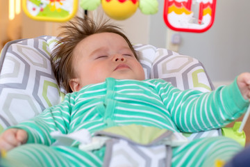 Obraz na płótnie Canvas Sleeping newborn baby boy napping in his bouncer