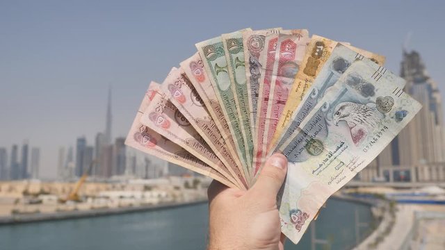 A man holds in his hand the money of the Arab Emirates. Hand close-up.