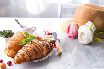 Fresh Croissant with berries and jam for breakfast, hat and flowers on white wooden stone , copy space
