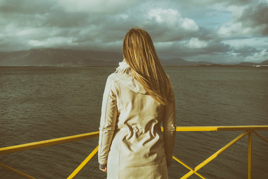 Woman standing at the harbor in Reykjavik and looking at the sea.