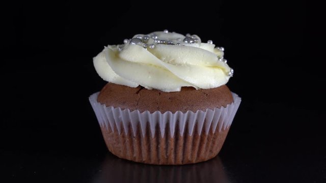 Fragrant, vanilla capcake with berry filling and honey cream cheese on black background, close up, rotates