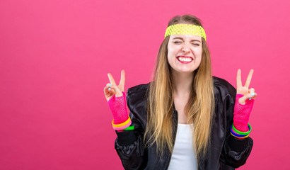 Woman in 1980's fashion giving the peace sign on a pink background