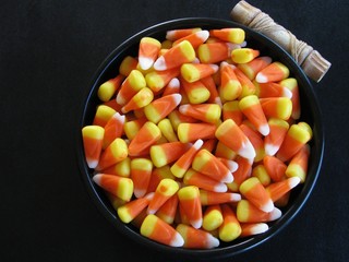 Bright candy corn in black bowl on black background