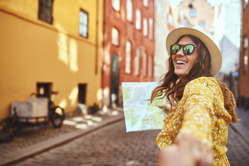 Smiling woman leading someone through the city by the hand