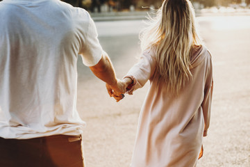 Crop couple holding hands on street