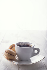 Tasty sweet macarons and coffee cup. Macaroons on white wooden background. Copy space