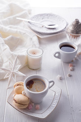 Tasty sweet macarons and coffee cup on white wooden background. Cristmas concept lazy morning, warm winter mood