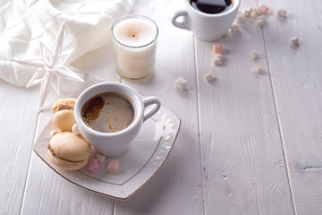 Tasty sweet macarons and coffee cup on white wooden background. Cristmas concept lazy morning, warm winter mood