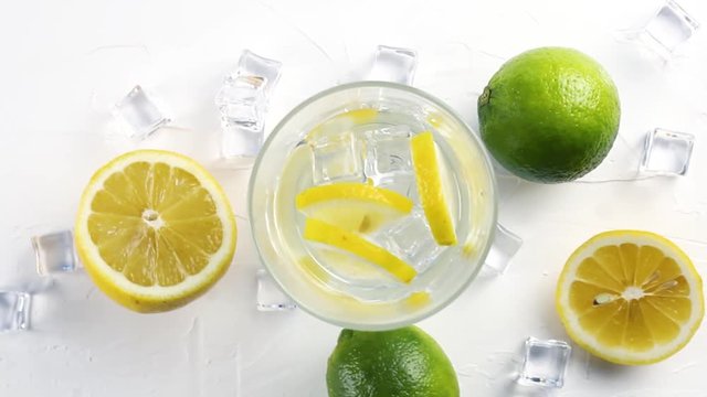 Lime and lemon with glass and ice cube on white background. Close up.
