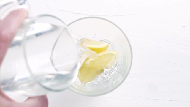 Hand put sliced lemon in glas with ice gubes. Clos up.