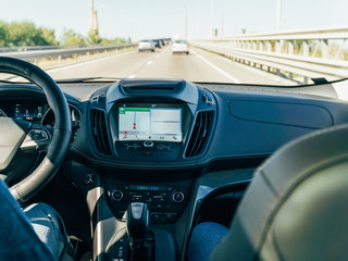 Dashboard View And GPS Map Of Modern Car With Hands Of Man Driver On Steering Wheel