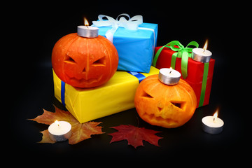 pumpkin, candles and gifts on a dark background