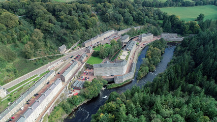 Fototapeta na wymiar Aerial image of the village of New Lanark. A World Heritage Site in a deep valley next to the River Clyde.