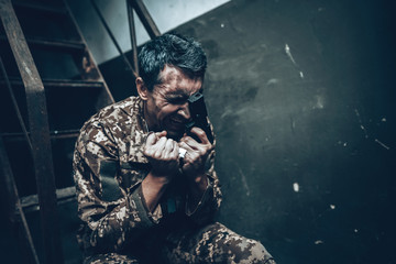 Soldier Is Sitting In War Shelter With Shotgun.