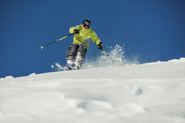 Male skier in yellow sportswear riding down the slope in Georgia, Gudauri