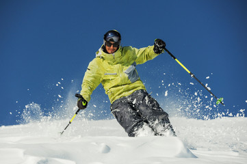 Happy skier in yellow sportswear riding down the slope in Georgia, Gudauri