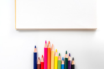 notepad with color pencil on white table view from above