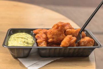 Fried pieces of fish, called kibbeling, with tasty remoulade sauce in a black plastic box with a plastic fork. Typical and very delicious dutch fast food, served as a meal in the netherlands.