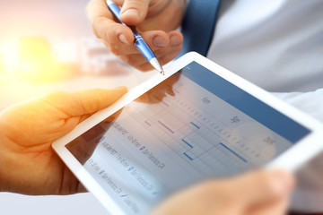 Business colleagues working and analyzing financial figures on a digital tablet