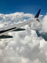 Freedom: Aerial view from above the clouds with a wing of an airplane in the sky over Cuba approaching the city of Havana (scenic journey over the ocean with beautiful view and cloudscape)