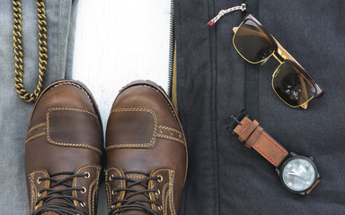 Fashionable concept, men’s clothes with brown boot  for bikers , coat, jeans, watch and sunglasses on white wooden background. pack shots, top view