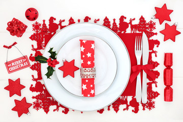 Christmas dinner table setting with porcelain plates, bauble decorations, napkin, cutlery and...