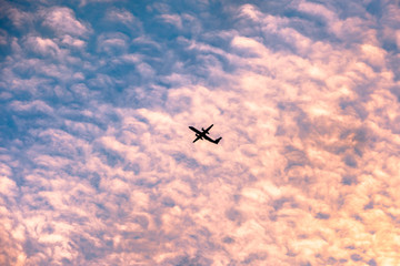 Passenger jet, airplane against the moody cloudscape as the sunsets on a summers eve.