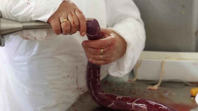 Close-up of man stuffing meat through saUSAge stuffer