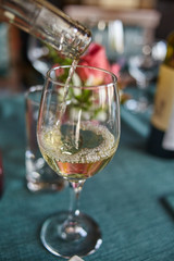 A beautiful glass in which white wine is poured from a bottle