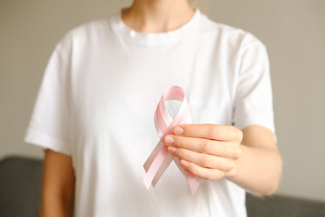 Woman in blank white t-shirt holding pink colored ribbon, international symbol of breast cancer awareness & moral support for survivors. Isolated background, copy space, close up, top view fat lay.
