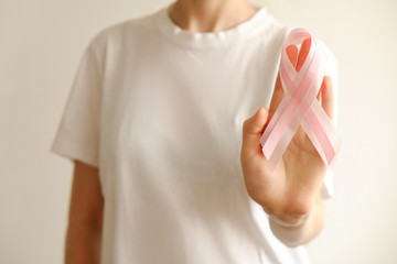 Woman in blank white t-shirt holding pink colored ribbon, international symbol of breast cancer...